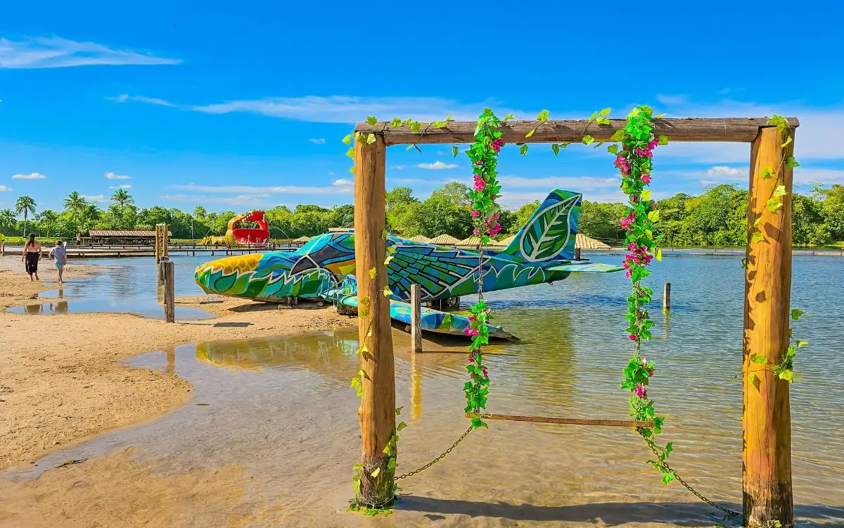 Área decorada à beira da água rasa da Praia da Figueira, espaço seguro para crianças